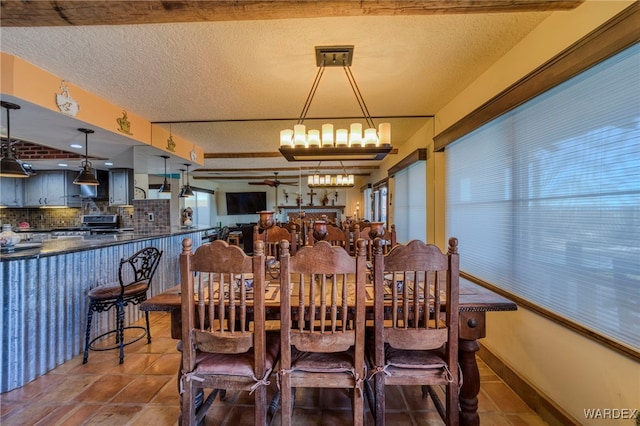 dining area featuring a textured ceiling, ceiling fan with notable chandelier, tile patterned flooring, and baseboards