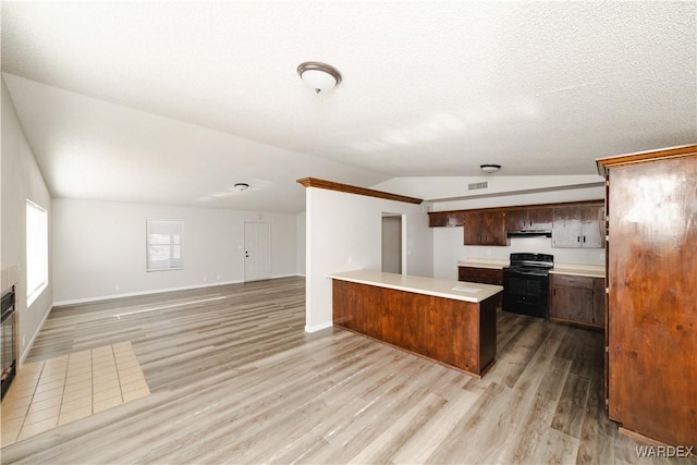 kitchen with light wood-style flooring, black range with electric cooktop, a peninsula, light countertops, and vaulted ceiling