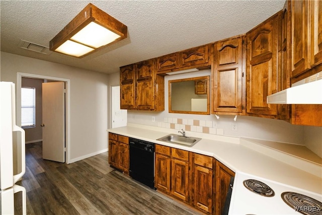 kitchen featuring a sink, a textured ceiling, dark wood finished floors, white appliances, and light countertops