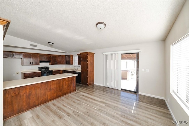 kitchen with visible vents, light countertops, a peninsula, black appliances, and a sink