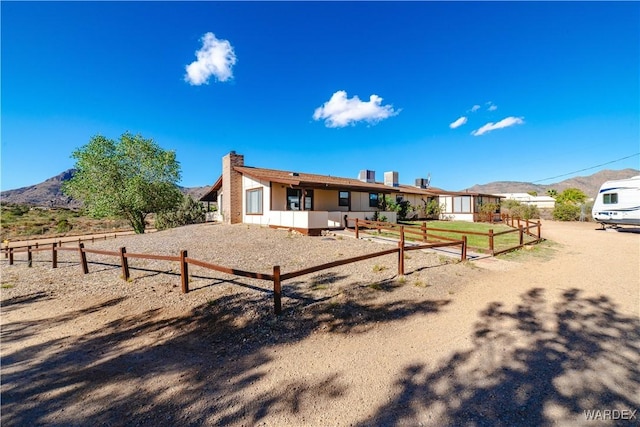 back of house featuring a mountain view, a chimney, and fence