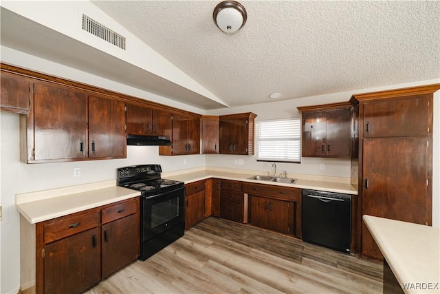 kitchen featuring visible vents, under cabinet range hood, vaulted ceiling, black appliances, and a sink