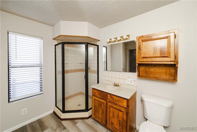 full bath with a shower stall, a textured ceiling, vanity, and wood finished floors