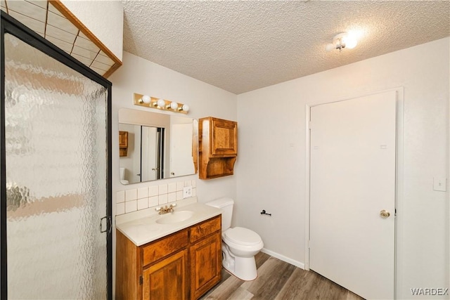 full bathroom with toilet, backsplash, wood finished floors, a shower stall, and vanity