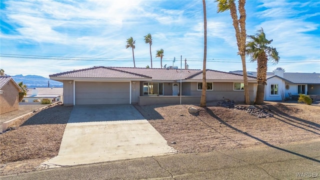 ranch-style house with a tile roof, stucco siding, concrete driveway, and a garage