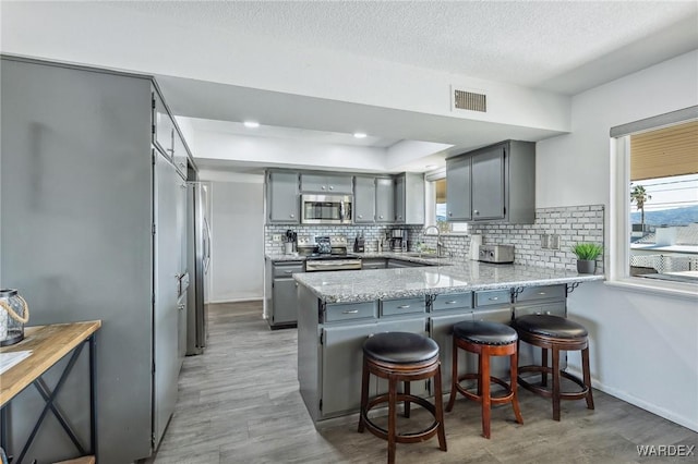 kitchen with a peninsula, visible vents, gray cabinets, and appliances with stainless steel finishes