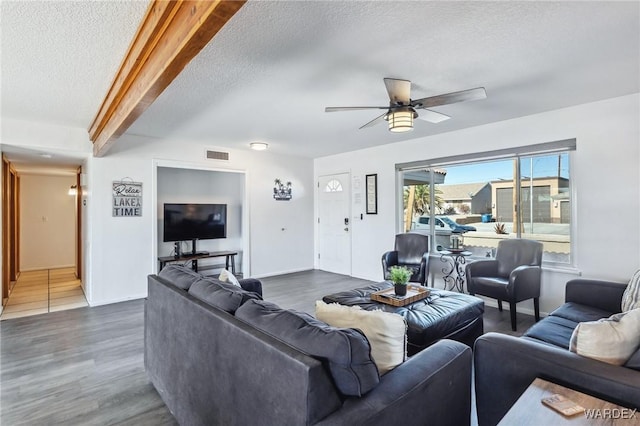 living area featuring visible vents, a textured ceiling, wood finished floors, and a ceiling fan