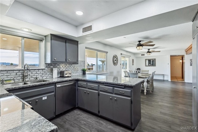 kitchen featuring visible vents, a sink, stainless steel dishwasher, a peninsula, and a healthy amount of sunlight