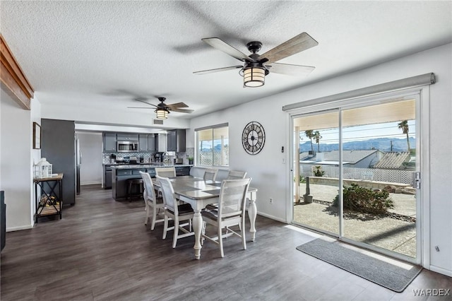 dining room with baseboards, dark wood-type flooring, ceiling fan, and a textured ceiling