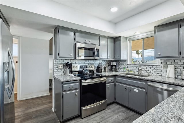 kitchen featuring a sink, appliances with stainless steel finishes, dark wood-style flooring, and gray cabinets