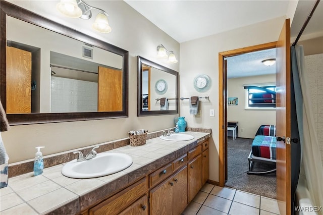 full bathroom with tile patterned flooring, visible vents, double vanity, and a sink