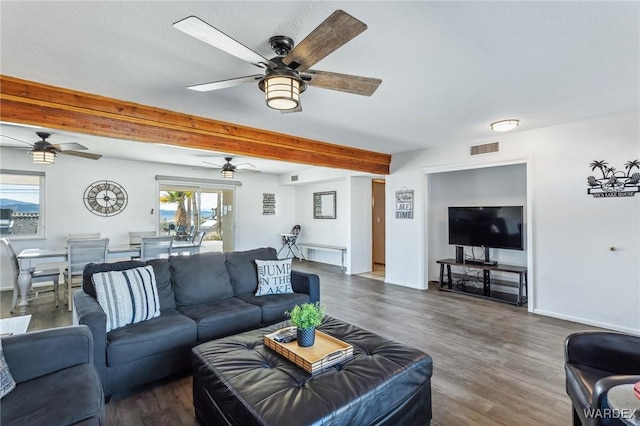 living room featuring beam ceiling, visible vents, baseboards, and wood finished floors