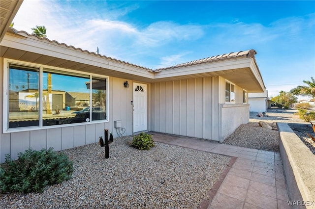 entrance to property featuring a tile roof and board and batten siding