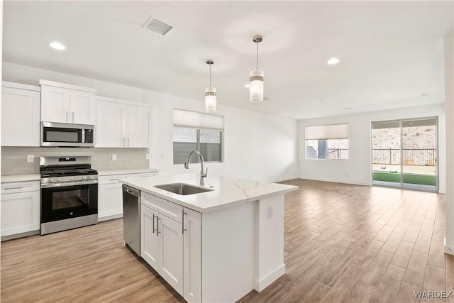 kitchen with appliances with stainless steel finishes, a sink, visible vents, and white cabinets