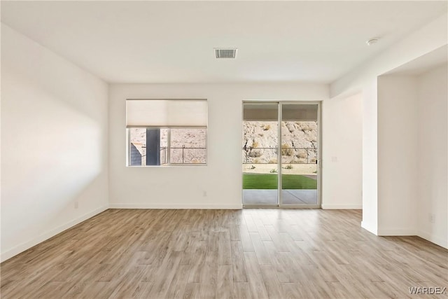 spare room featuring light wood-style floors, baseboards, and visible vents