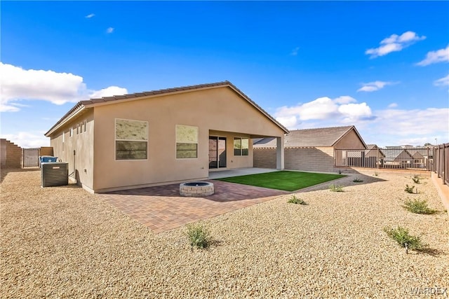 back of house featuring stucco siding, a patio area, cooling unit, a fenced backyard, and a fire pit