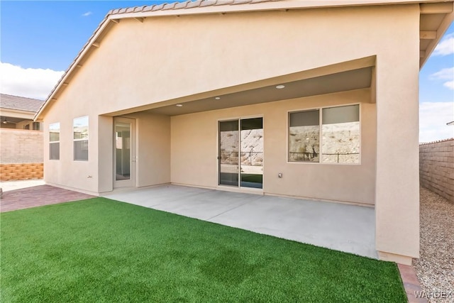 rear view of property featuring a patio, fence, and stucco siding