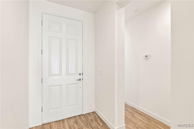 doorway featuring light wood-style flooring and baseboards