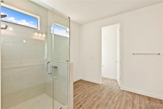 full bath with a shower stall, baseboards, and wood finished floors