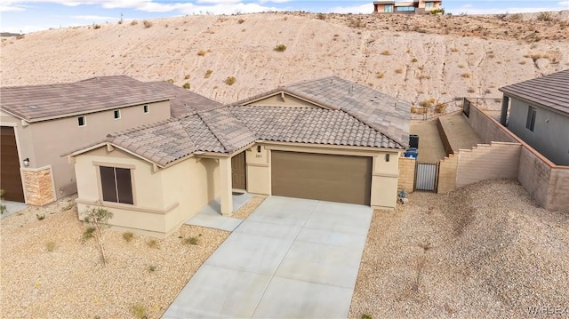 view of front of house featuring an attached garage, fence, a tiled roof, concrete driveway, and stucco siding