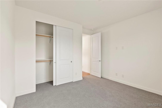 unfurnished bedroom with baseboards, a closet, and light colored carpet