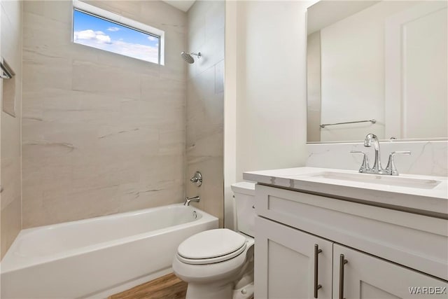 bathroom with toilet, washtub / shower combination, wood finished floors, and vanity