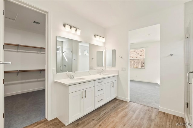 bathroom featuring a spacious closet, visible vents, a sink, and wood finished floors