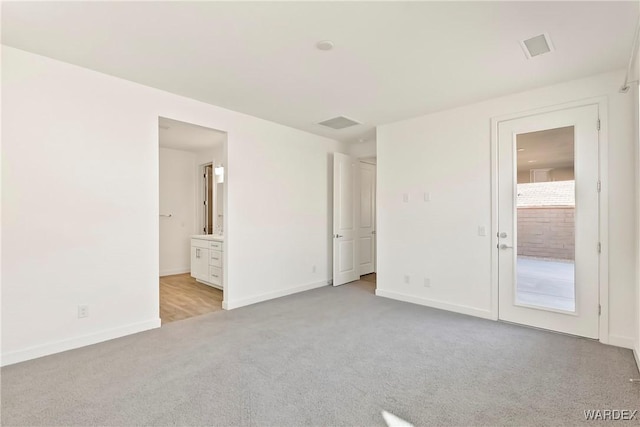 unfurnished bedroom with light carpet, ensuite bath, visible vents, and baseboards