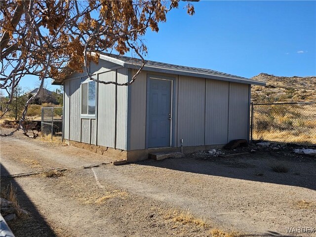 view of outbuilding with dirt driveway and fence