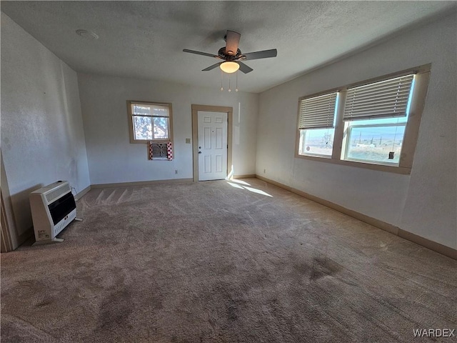 unfurnished living room featuring baseboards, a ceiling fan, heating unit, a textured ceiling, and carpet flooring