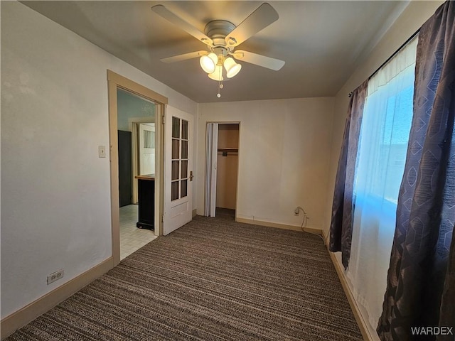 interior space with baseboards, a ceiling fan, and light colored carpet