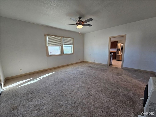 spare room with light carpet, a textured ceiling, a ceiling fan, and baseboards