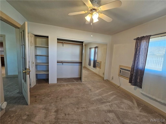 unfurnished bedroom with multiple windows, a wall mounted AC, carpet flooring, and multiple closets