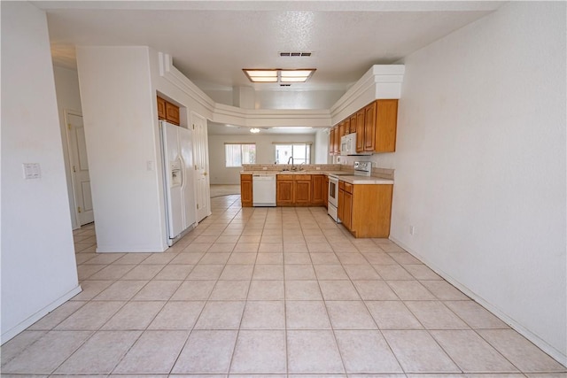 3103 Crater Dr, Lake Havasu, AZ 86404 - kitchen featuring white appliances, a sink, light countertops, a peninsula, and brown cabinets