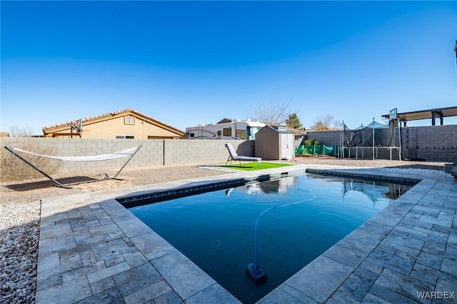 view of pool featuring a fenced backyard, a trampoline, an outbuilding, and a shed