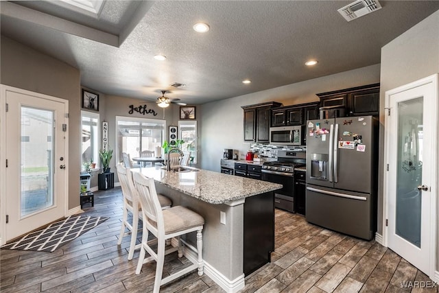 kitchen featuring appliances with stainless steel finishes, a sink, visible vents, and wood tiled floor