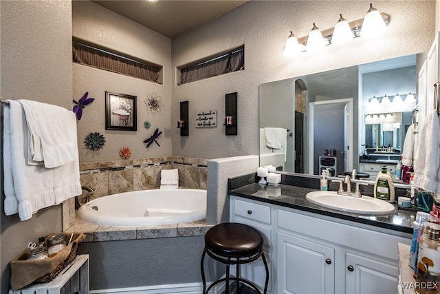 bathroom featuring a textured wall, a garden tub, and vanity