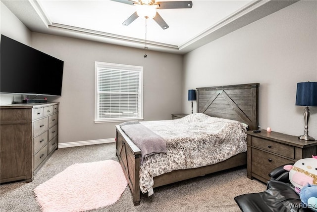 bedroom with a raised ceiling, light carpet, ceiling fan, and baseboards