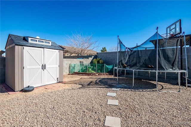 exterior space with a trampoline, a fenced backyard, an outdoor structure, and a storage unit