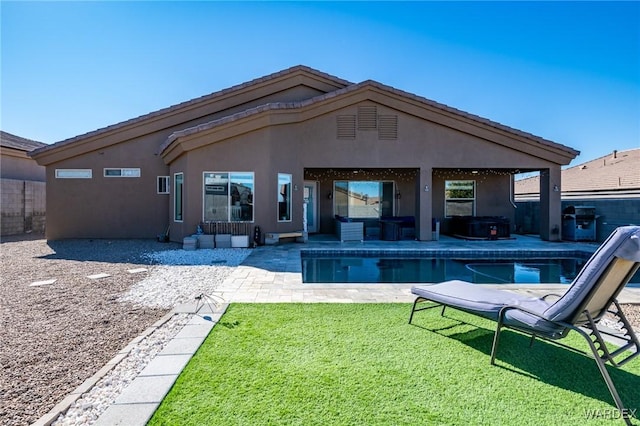 rear view of property with a fenced in pool, a patio, a lawn, and stucco siding