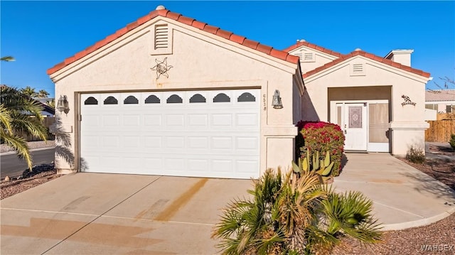 mediterranean / spanish-style home with driveway, an attached garage, a tile roof, and stucco siding