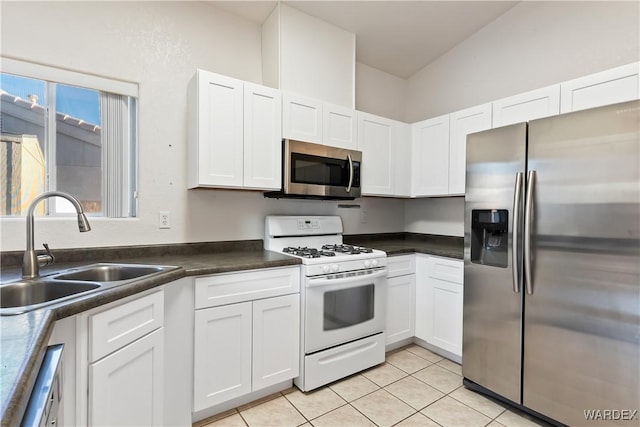 kitchen featuring stainless steel appliances, light tile patterned flooring, a sink, and white cabinetry