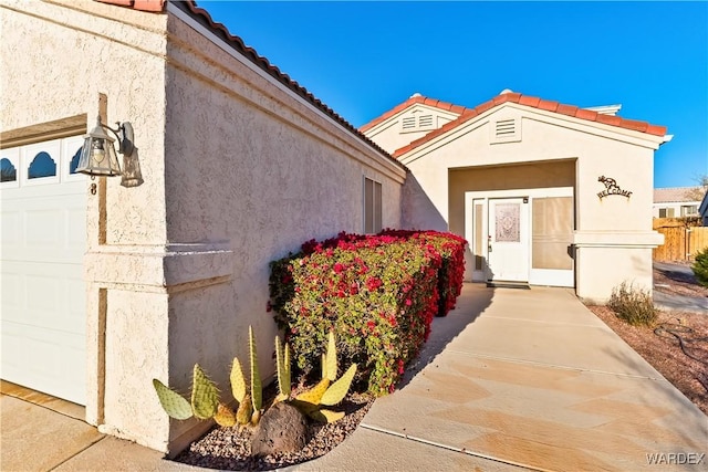 property entrance featuring a garage, a tiled roof, and stucco siding