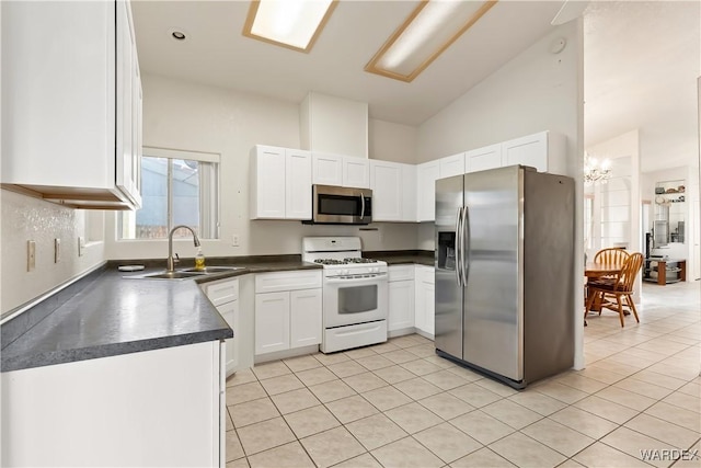 kitchen featuring light tile patterned floors, stainless steel appliances, a sink, white cabinetry, and dark countertops