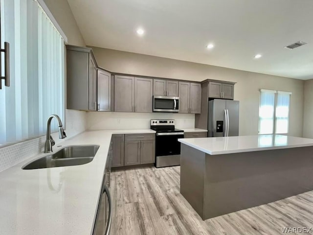 kitchen featuring stainless steel appliances, light countertops, visible vents, light wood-style flooring, and a sink