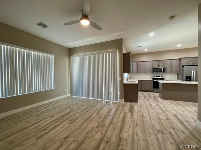 kitchen with appliances with stainless steel finishes, light countertops, a sink, and open floor plan