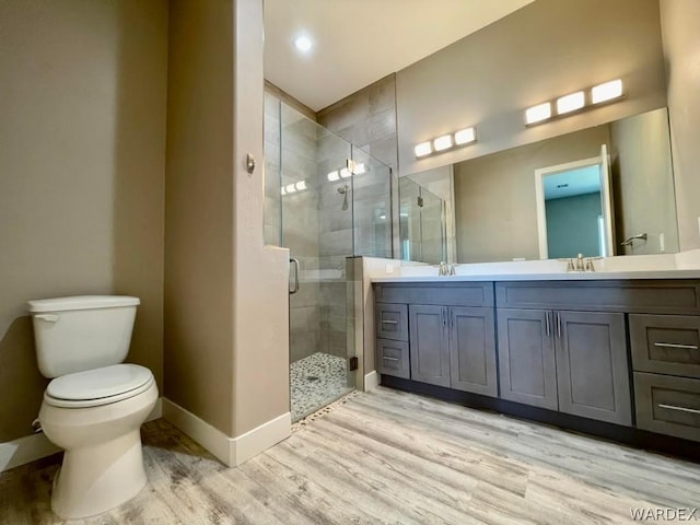 bathroom featuring a sink, wood finished floors, baseboards, double vanity, and a stall shower