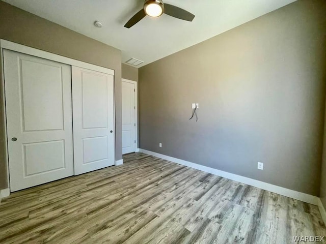 unfurnished bedroom featuring light wood finished floors, a closet, and baseboards