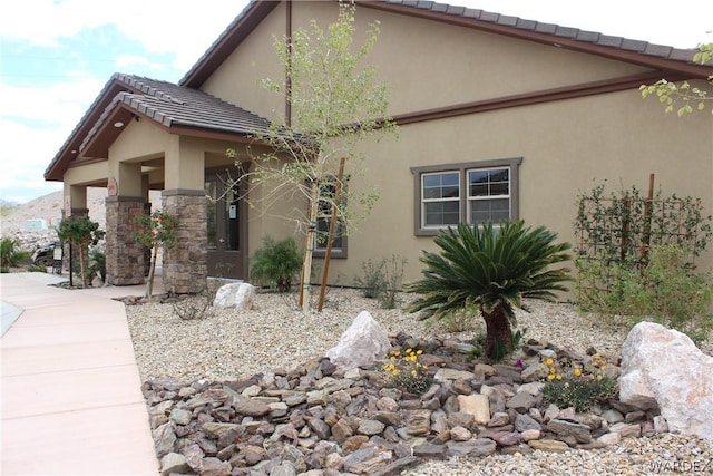 view of side of property with stone siding, a tile roof, and stucco siding