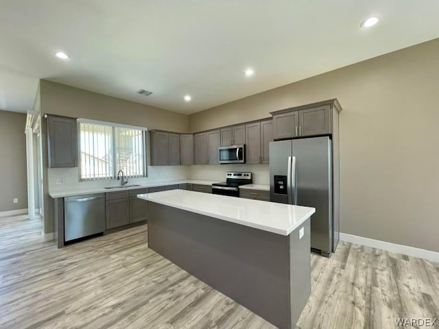 kitchen with a sink, stainless steel appliances, light countertops, and a center island